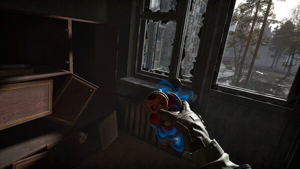Screenshot from Into the Radius 2 shows a hand holding a doll in a dim room with broken windows and trees visible outside.