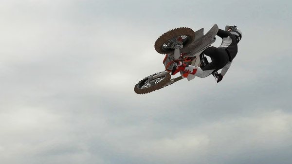 MX Bikes screenshot: A motorcyclist performs a high-flying stunt against a cloudy sky backdrop, showcasing dynamic gameplay.