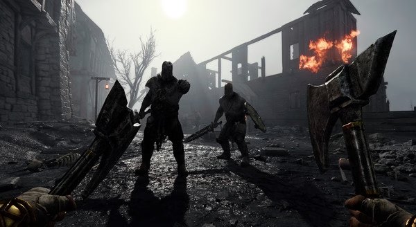 A Warhammer: Vermintide 2 screenshot showing two armored enemies approaching in a ruined, fire-lit village as axes are wielded in view.