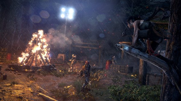 Screenshot from Rise of the Tomb Raider showing a character perched on a tree, observing a campfire scene in a rainy forest.