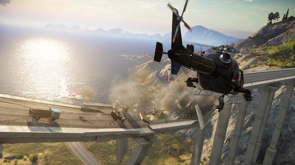 A helicopter swoops over a destroyed bridge in this Just Cause 3 screenshot, with smoke and vehicles scattered below.