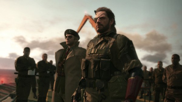 Screenshot from Metal Gear Solid V: The Phantom Pain showing a group of soldiers standing together under a cloudy sky.