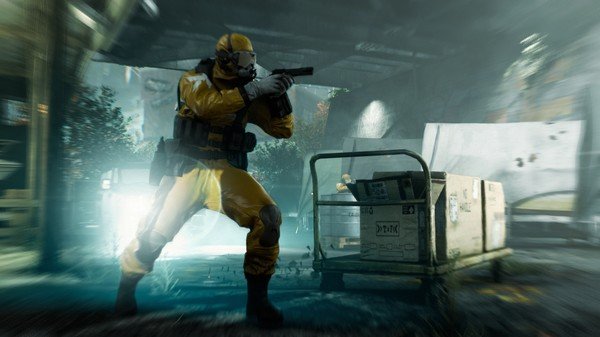 Quantum Break screenshot: A character in a yellow hazmat suit holds a gun, standing near a crate in a dimly lit industrial setting.