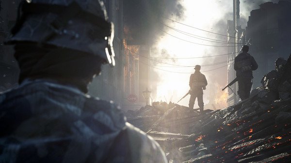 Battlefield V screenshot: Soldiers navigate a war-torn street with debris, fire, and smoke under a bright, hazy sky.