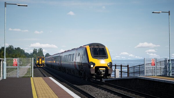 Train Sim World 6 screenshot: Two modern trains pass each other on a coastal track under a clear sky.