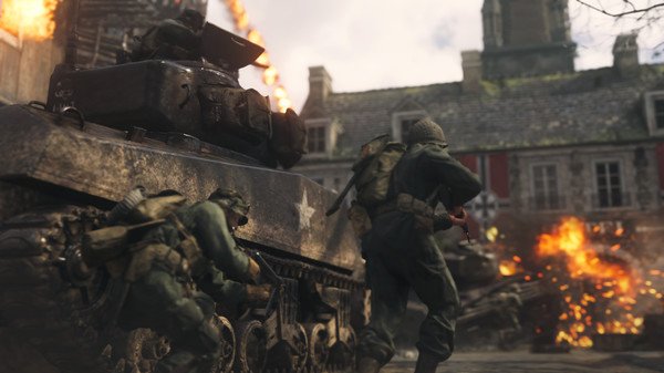 Call of Duty: WWII screenshot showing soldiers advancing beside a tank in a war-torn village with explosions in the background.