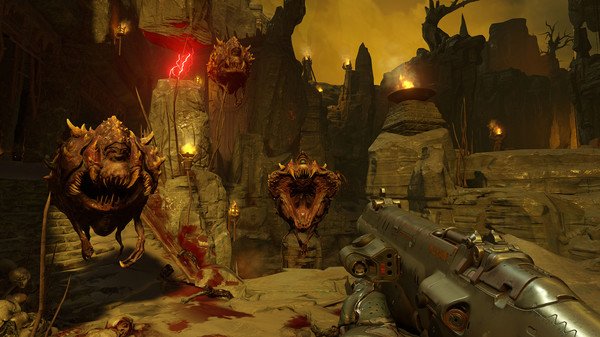 A DOOM screenshot showing a player aiming a shotgun at floating demon enemies in a fiery, rocky landscape with torches.